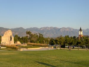 Idyllic park scene with a statue and mountains during daytime.