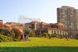 People walking on a grassy hill with buildings in background