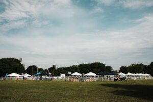 An outdoor event setup in a Chicago park featuring tents, grass, and a sunny summer day.