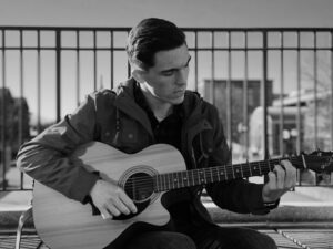 Monochrome photo of a man playing an acoustic guitar outdoors in Frederick, MD.
